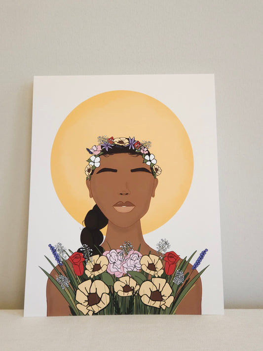 Growing and Glowing art print by Crystal Shaw owner of World of Shaw. Image of woman with brown skin in front of the sun. Assorted Flowers are on her head and a bouquet of assorted flowers is in front of her.